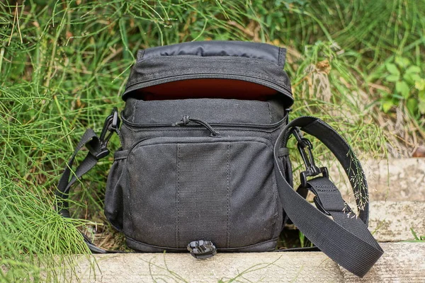 one black open cloth bag stands on a gray table among the green grass in the street