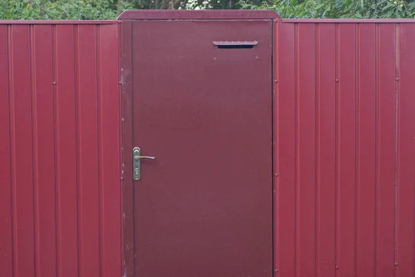 One Closed Red Metal Door Iron Fence Wall Rural Street — Zdjęcie stockowe
