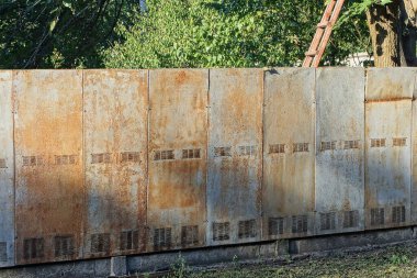 part of an old gray private metal fence wall in brown rust on the street