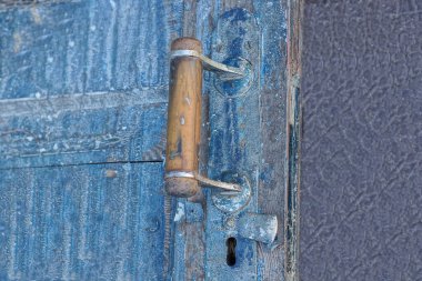 one old brown doorknob on a blue wooden door in the street