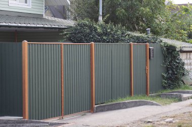 large closed metal green gate and door on the fence wall on the street