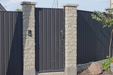 Metal ve tuğladan yapılmış gri bir duvarın üzerinde kapalı bir demir kapı. 