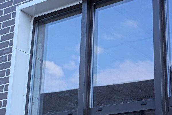 one large window with a black frame on a white gray brick wall in the street