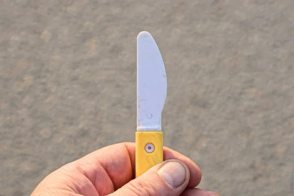Ruka Drží Bílý Žlutý Plastový Malý Nůž Šedém Pozadí — Stock fotografie