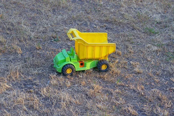 Jeden Plastikowy Żółty Zielony Samochód Zabawki Stoi Suchej Trawie Szarej — Zdjęcie stockowe