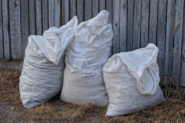 Three Large White Garbage Bags Stand Dry Grass Gray Fence — Stock Photo, Image
