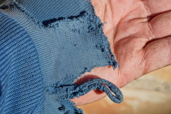 古いものは手に布で作られた青い袖を引き裂いた — ストック写真