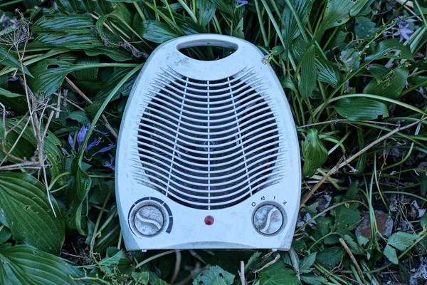 one white mobile dirty fan lies on green plant  and the ground in nature