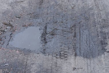 Yolun gri zemininde kirli su birikintisi var.