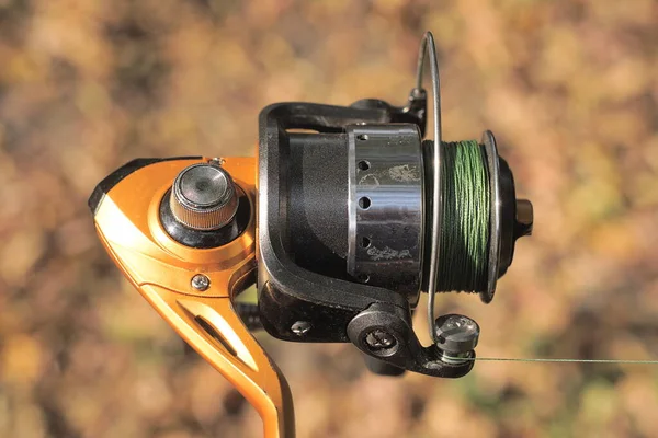 one metallic brown black spinning reel with green line outdoors