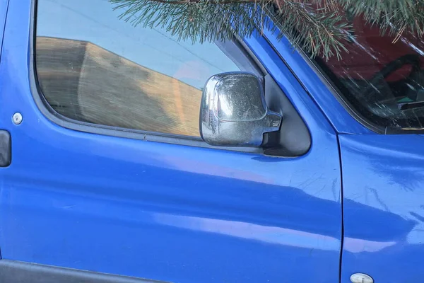 one gray metal review mirror hanging on a blue car in the street