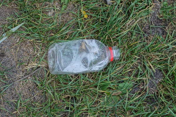 空の小さな白いペットボトルから出るゴミは自然界の緑の芝生の上に — ストック写真