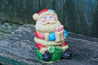 Bir plastik renkli Noel Baba oyuncağı gri tahta bir masada duruyor.