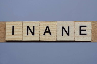 Gri bir masanın üzerinde siyah yazı tipi olan kahverengi ahşap harflerden anlamsızca yazılıyor.