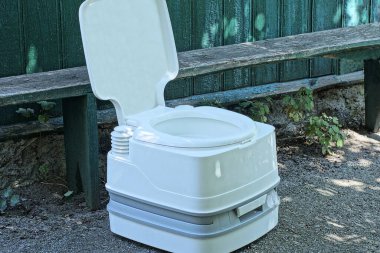 one plastic white mobile open dry closet stands on gray asphalt near a green wooden wall on the street