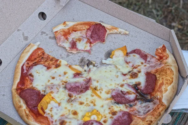 food and pieces of fresh colored pizza in a gray paper carton box
