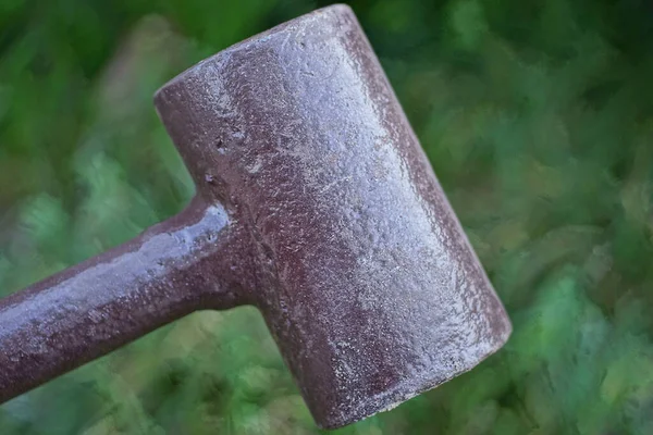 室外绿色背景上的一个大褐色铁锤 — 图库照片