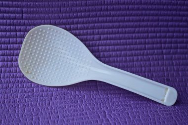 Bir beyaz boş plastik kaşık leylak masasında yatıyor.