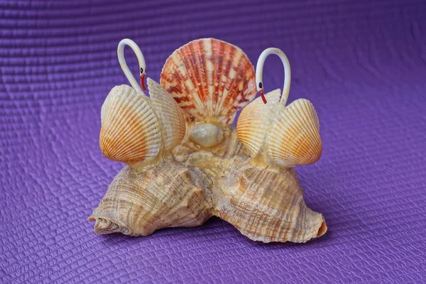 a souvenir figurine of brown seashells glued into a composition stands on a purple table