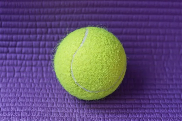 one yellow tennis ball lies on a purple table