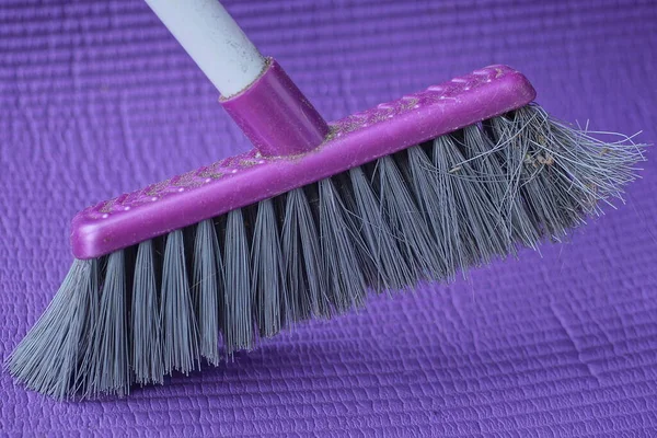 一只灰色的塑料扫帚矗立在紫色的地板上 — 图库照片