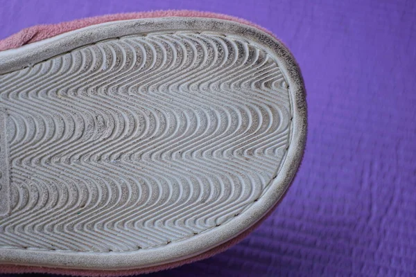 part of one old dirty gray white plastic shoe sole on a purple background