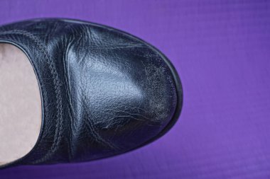 Mor arkaplandaki siyah deri ayakkabının bir parçası.