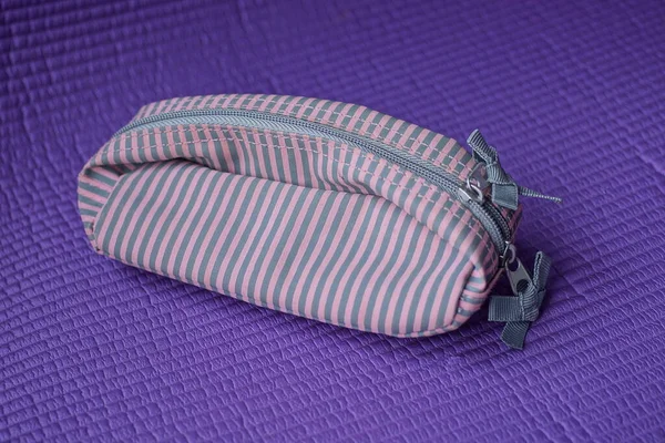 一个小的 密闭的 带条纹的粉色灰色布袋躺在紫丁香桌上 — 图库照片