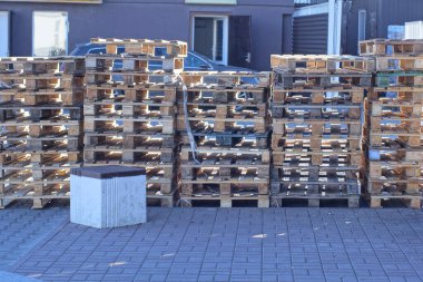 Bir sıra eski kahverengi ahşap paletler sokağın gri kaldırımında duruyor.