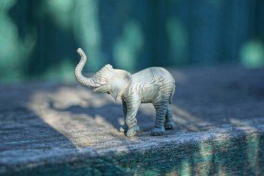 Plastik gri plastik bir filin küçük bir heykeli yeşil bir arka planda duruyor.