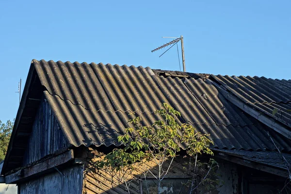 青い空に対して灰色のスレート屋根の下の古い農村の家の緑の木製の屋根裏部屋 — ストック写真