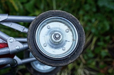Küçük kirli siyah metal ve plastik tekerlek yeşil bir arka planda açık bir tramvayda