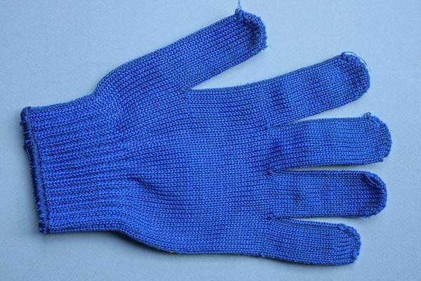 one new work glove made of blue  fabric lies on a gray table