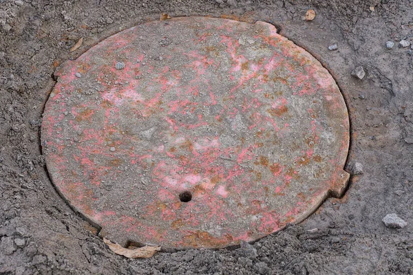 一条旧的红色锈迹斑斑的下水道在街上的地面上孵化 — 图库照片