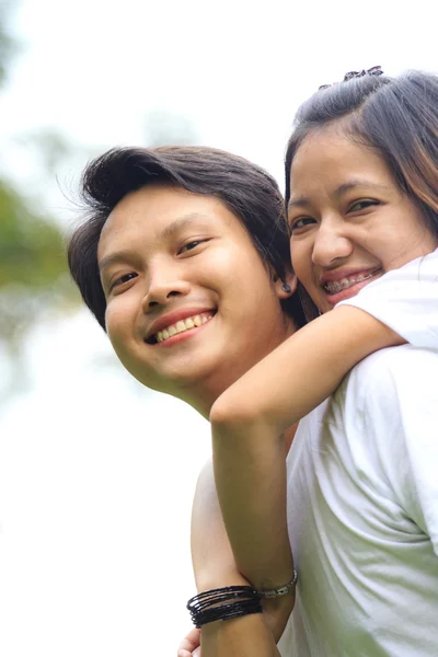 Young woman embracing man from behind in park — Stock Photo, Image