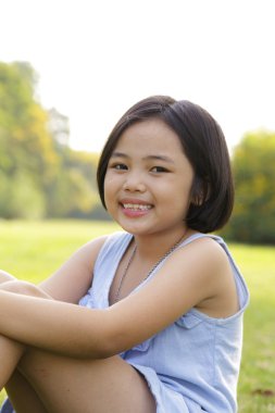 Asyalı küçük kız parkta mutlulukla gülümseyerek