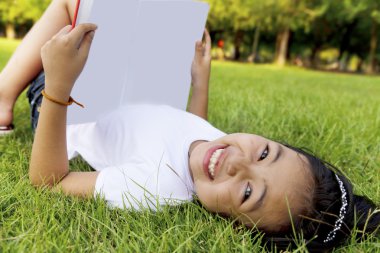 Asyalı küçük kız rahatla ve park kitap okuma