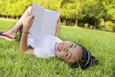 Asyalı küçük kız rahatla ve park kitap okuma