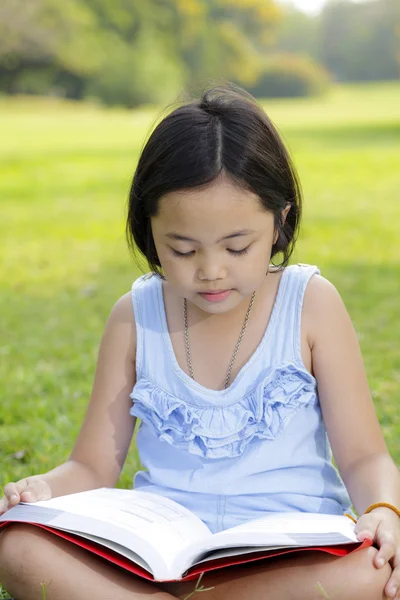 Asiatique petite fille lecture livre dans le parc — Photo