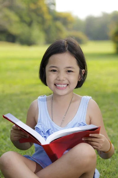 Asian little girl reading book in the park — Stock Photo, Image
