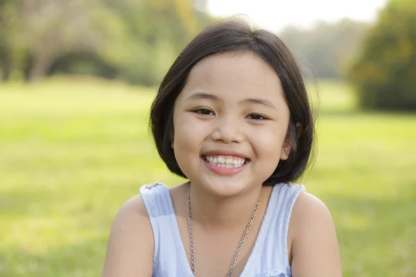 Asiatisches kleines Mädchen lächelt glücklich im Park — Stockfoto