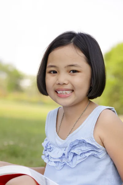 Asiatisches kleines Mädchen liest Buch im Park — Stockfoto