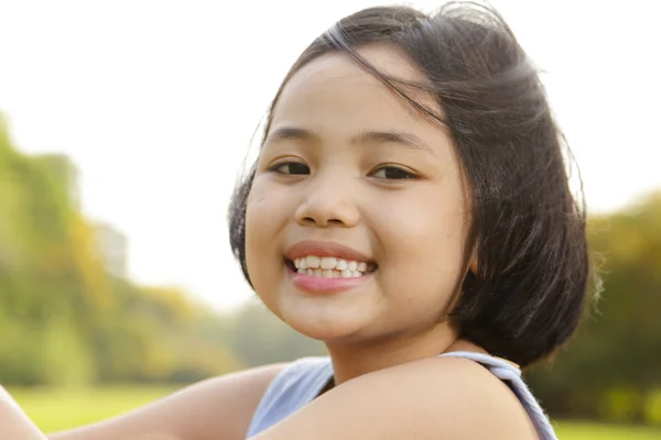 Asiatiska lilla flickan ler glatt i parken — Stockfoto