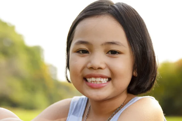 Asiatisches kleines Mädchen lächelt glücklich im Park — Stockfoto