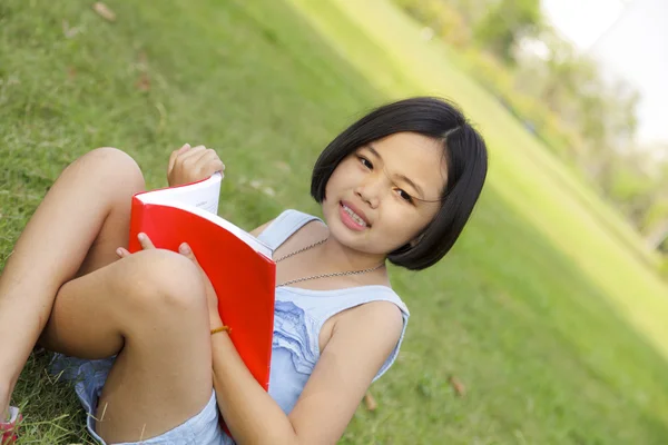 Aziatische little girl leesboek in het park — Stockfoto