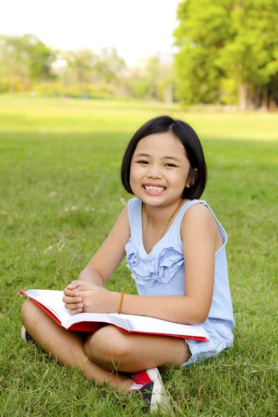 Азиатская девочка читает книгу в парке — стоковое фото