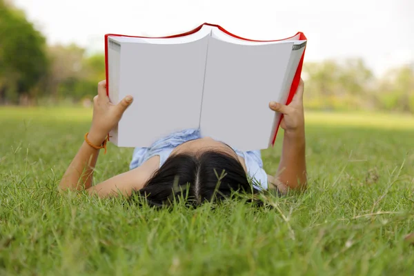 Asian little girl reading book in the park — Stock Photo, Image