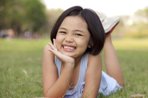 Asiatisches kleines Mädchen entspannt sich und lächelt glücklich im Park — Stockfoto