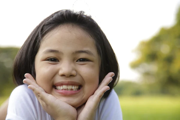 Asiática niña relajarse y sonreír felizmente en el parque —  Fotos de Stock