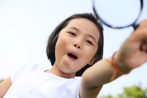Asiática niña sosteniendo un lupa en al aire libre —  Fotos de Stock
